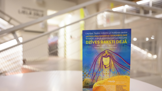 Uz galda novietots krāsains plakāts modernā, gaišā interjerā ar izplūdušu fonu