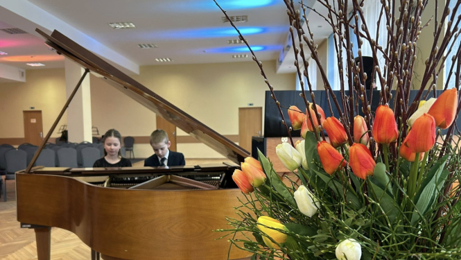 Ziedi un klavieres pie kurām zēns un meitene