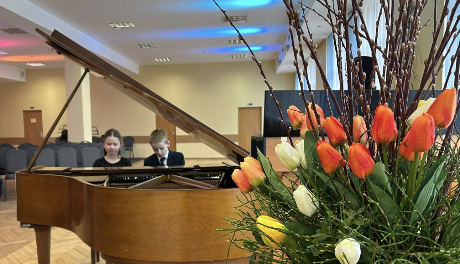 Ziedi un klavieres pie kurām zēns un meitene